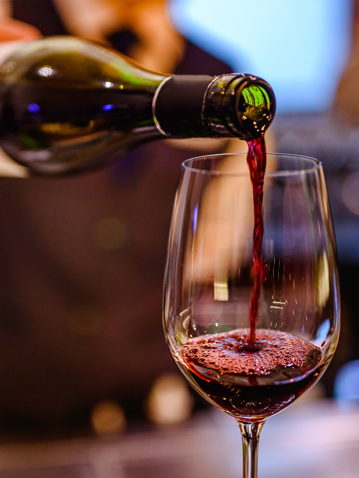 Jemand gießt Rotwein in ein Glas